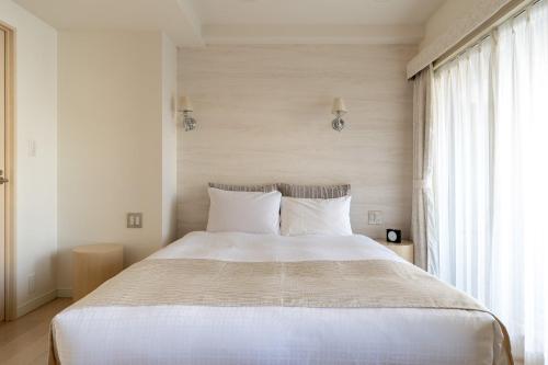 a bedroom with a large white bed with white pillows at Tokyu Stay Aoyama in Tokyo