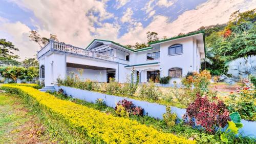 a white house with a garden in front of it at Samanea House Deluxe, big pool, 10min from PV in Hone Creek