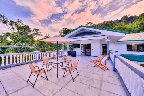 a patio with chairs and a table with an umbrella at Samanea House Deluxe, big pool, 10min from PV in Hone Creek