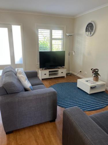 a living room with a couch and a flat screen tv at Poppies Lakeview Terrace - 2 Bedroom in Cams Wharf