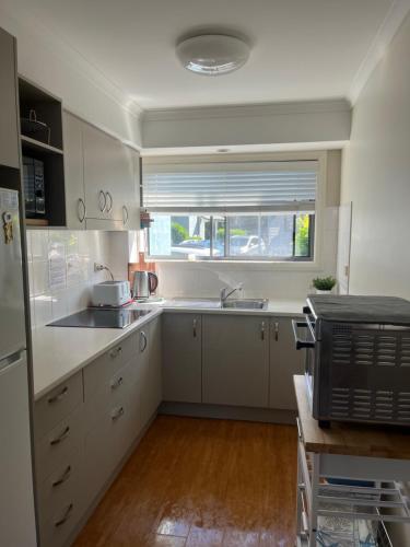 a kitchen with white cabinets and a sink and a window at Poppies Lakeview Terrace - 2 Bedroom in Cams Wharf