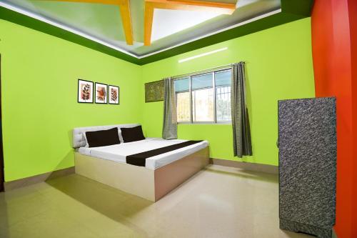 JalpāiguriにあるHotel O Shiv Shakti Homestayの緑のベッドルーム(ベッド1台、窓付)