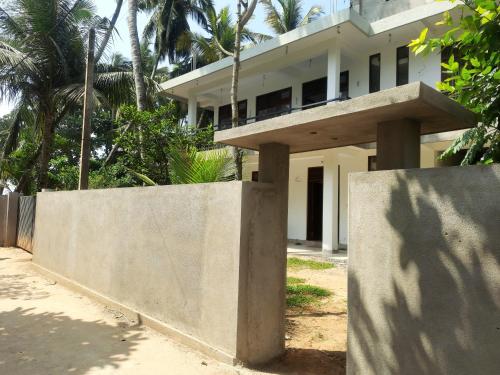 a concrete wall in front of a house at Turtle Point Homestay in Batigama