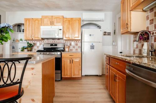 a kitchen with wooden cabinets and a white refrigerator at NEW! Family-Friendly Getaway -1 Mi to Dtwn Salem w Roof Deck & Tiki Bar in Salem
