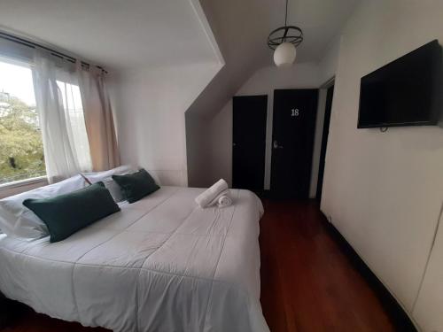 a bedroom with a large white bed with a window at Atacama Hostel Backpackers in Santiago