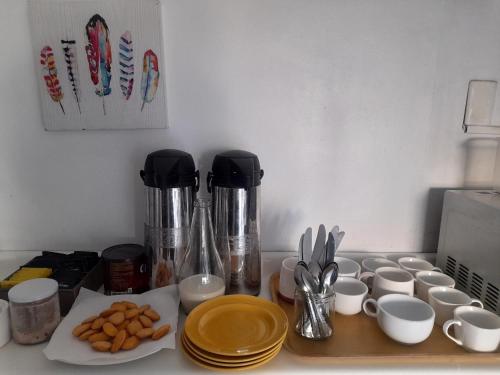 a kitchen counter with cups and utensils and coffee makers at Atacama Hostel Backpackers in Santiago