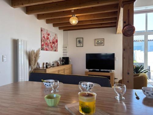 a dining room table with glasses on it with a television at Gîte chaleureux avec jardin clos en Auvergne - FR-1-489-573 in Saint-Bonnet-de-Rochefort