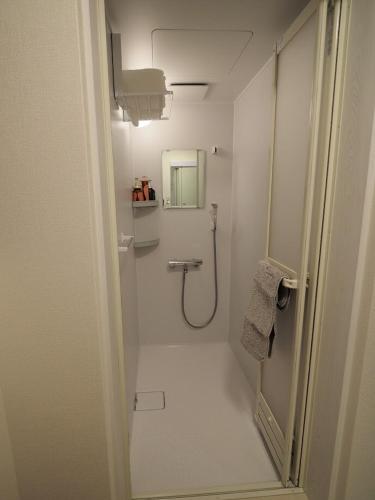 a white bathroom with a shower and a mirror at 映画館みたいなお部屋で非日常体験 キッチン付きで家族も安心 1日1組限定貸切ステイ シンカイハウス in Izu