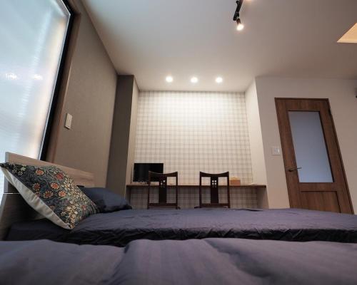 a bedroom with a bed and a table with two chairs at 映画館みたいなお部屋で非日常体験 キッチン付きで家族も安心 1日1組限定貸切ステイ シンカイハウス in Izu