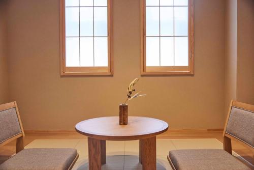 a table and two chairs in a room with two windows at MKG HOTEL Asakusa in Tokyo