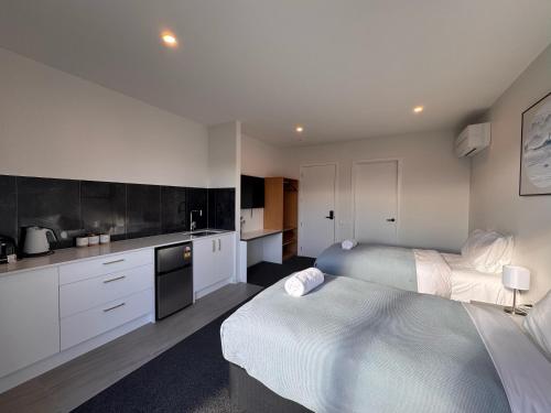 a bedroom with two beds and a kitchen with white cabinets at Luminous Tekapo in Lake Tekapo