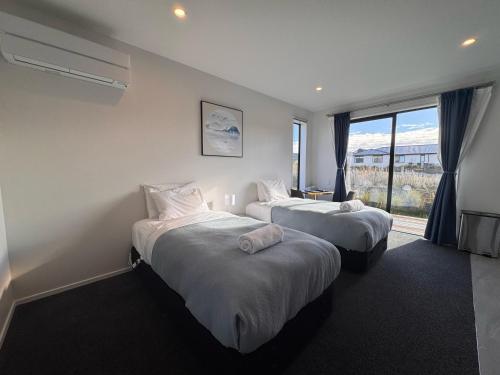two beds in a hotel room with a window at Luminous Tekapo in Lake Tekapo