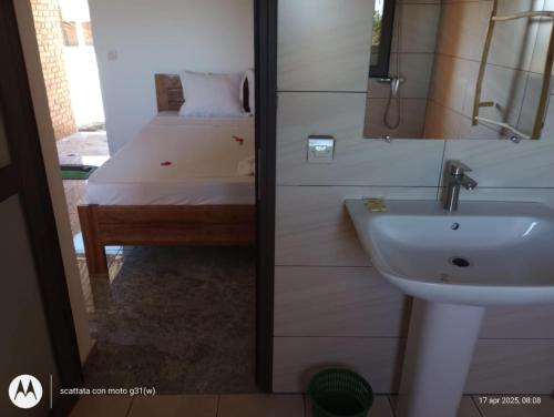 Un baño con lavabo y una cama en una habitación. en Chambre d'hôte Ristorante Pizzeria Liberta, en Ranohira