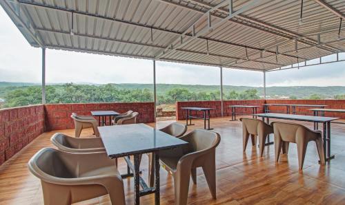 a restaurant with tables and chairs and a view at Treebo The Venna Hill in Mahabaleshwar
