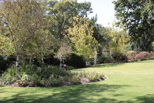 a green lawn with trees and bushes in a park at Vredenburg Manor House in Somerset West