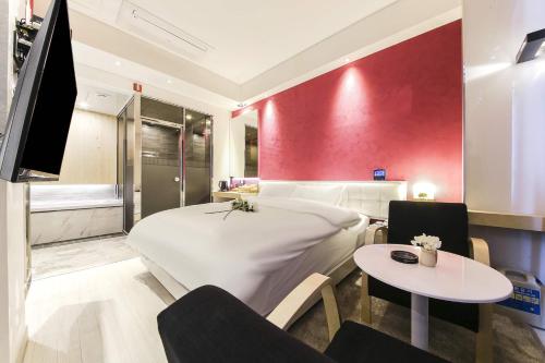 a bedroom with a large white bed and a table at Hotel OSCAR in Daegu