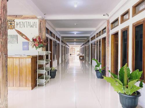 a hallway of a building with potted plants at Bujai Mentawai Griya Hotel in Tuapejat