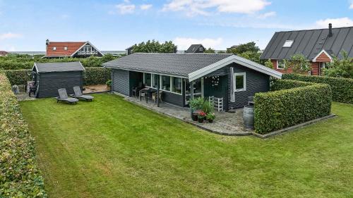 a small house in a yard with a green lawn at Cozy Little Holiday Home Near The Beach in Otterup