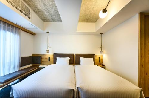 two twin beds in a room with a window at Tassel Hotel Sanjo Shirakawa in Kyoto