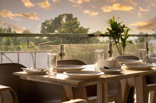 a wooden table with plates and glasses on a balcony at Perfectstayz Koko Maya 5 mins walk to beach in Morjim