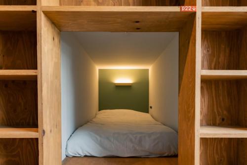 a small room with a bed in the middle of a room at NOVELS Hostel and cafe bar and Books in Komoro