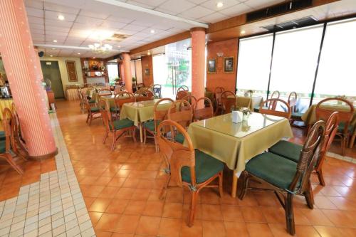Un comedor con mesas y sillas en un restaurante. en Pin Hotel, en Lampang