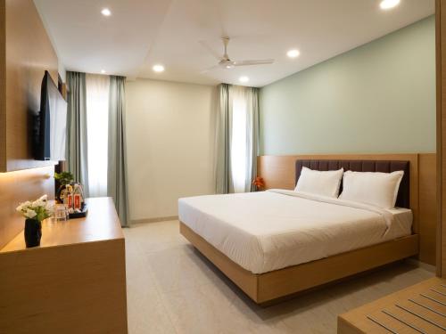a bedroom with a large white bed and a desk at Hotel Orchid Suites Kokapet, Business Hotel in Hyderabad