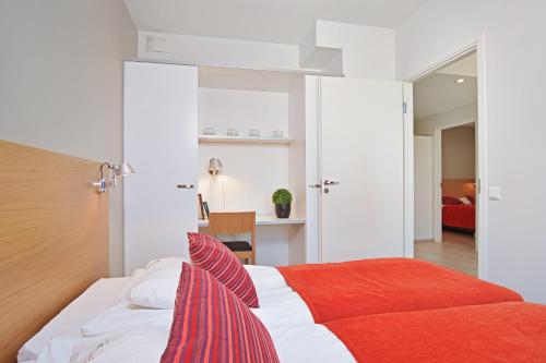 - une chambre avec un lit et une couverture rouge dans l'établissement Forenom Serviced Apartments Tampere Pyynikki, à Tampere