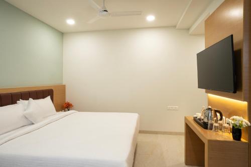 a bedroom with a bed and a flat screen tv at Hotel Orchid Suites Kokapet, Business Hotel in Hyderabad
