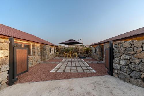 a stone building with a patio with a table and an umbrella at Stay Onwol in Kwidŏng-ni