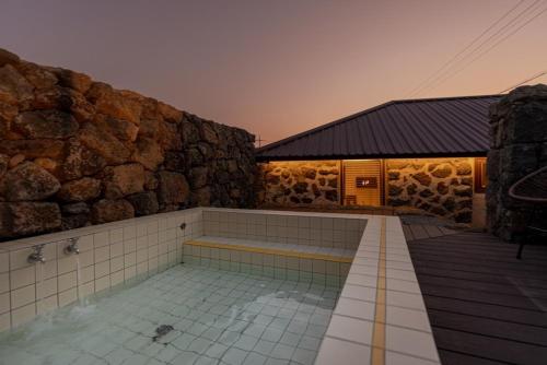 a building with a hot tub and a stone wall at Stay Onwol in Kwidŏng-ni