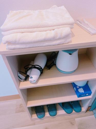 a shelf in a doll house with shoes and a towel at ひまわりHotel in Nagasaki