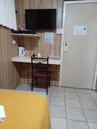 a room with a desk with a television and a chair at Civic Motel Grafton in Grafton