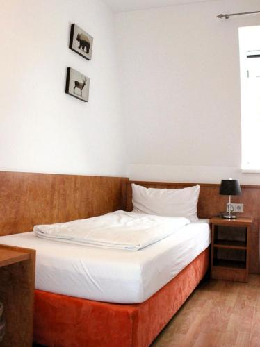 a bedroom with a bed with white sheets and a window at Hotel Waitzingers in Landsberg am Lech
