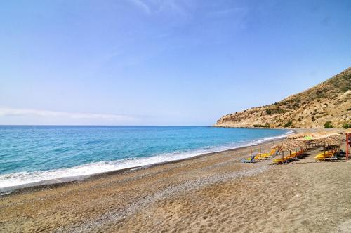 a beach with lounge chairs and the ocean at Atelier Myrtos Mare in Myrtos