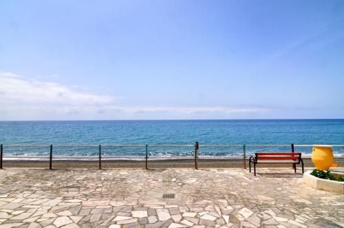 a red bench sitting next to the ocean at Atelier Myrtos Mare in Myrtos