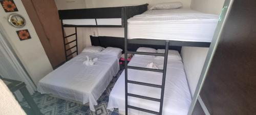 two bunk beds in a room with white sheets at Casita de Descanso con Alberca o Piscina in Tuxpan de Rodríguez Cano