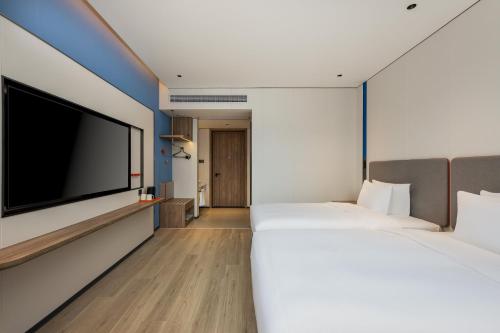 two beds in a hotel room with a flat screen tv at Holiday Inn Express Shangrao Railway Station by IHG in Shangrao