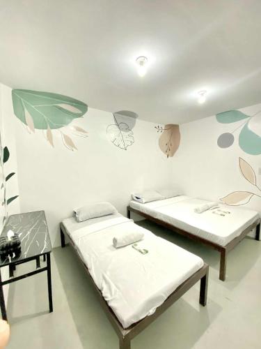 two beds in a room with flowers painted on the wall at Inn Convenience in Coron