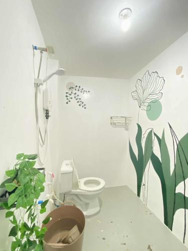 a bathroom with a toilet and flowers on the wall at Inn Convenience in Coron