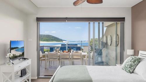 a bedroom with a bed and a balcony with a table and chairs at Solaris in Fingal Bay