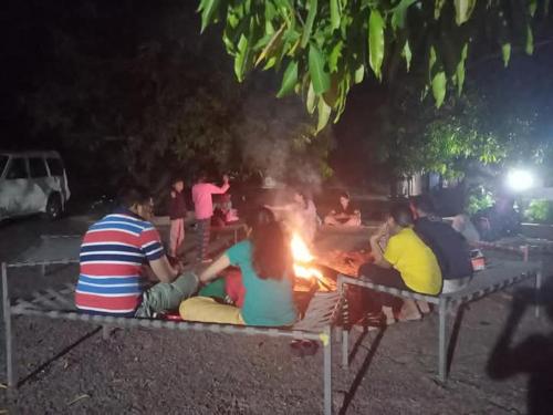 a group of people sitting around a fire at night at Van Vagdo Prakruti Nivas in Sāsan Gīr