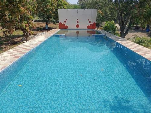 a large blue swimming pool with a sign in the background at Van Vagdo Prakruti Nivas in Sāsan Gīr