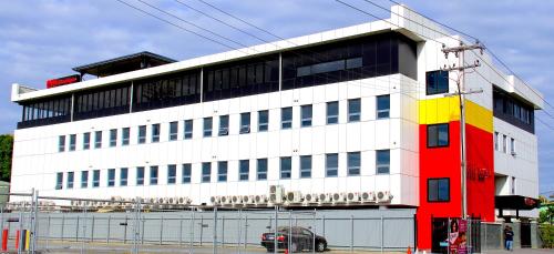 a red white and yellow building on a street at Citi Boutique Hotel - Lahara Avenue in Port Moresby