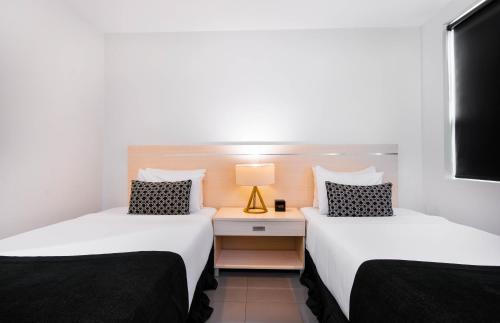two beds in a room with a desk with a lamp at Citi Boutique Hotel - Lahara Avenue in Port Moresby