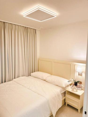a bedroom with a white bed and a nightstand with a bed sidx sidx sidx at Atelier PADO 101 in Busan