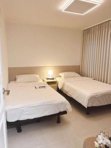 a hotel room with two beds and a lamp at Atelier PADO 101 in Busan