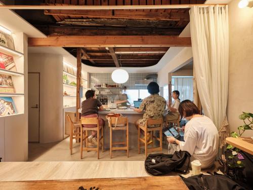 a group of people sitting at a table in a kitchen at Tipy records inn photon in Odawara