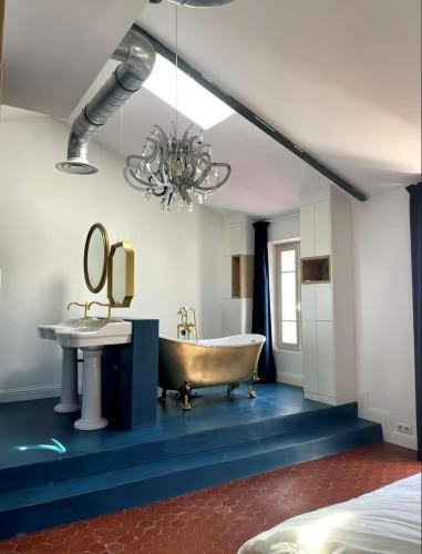 une salle de bain avec une baignoire, un lavabo et un lustre dans l'établissement Maison au cœur du Mourillon avec Jacuzzi, à Toulon