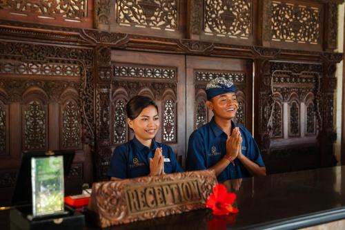 a man and a woman standing next to a table with a cake at Vila Ombak in Gili Trawangan